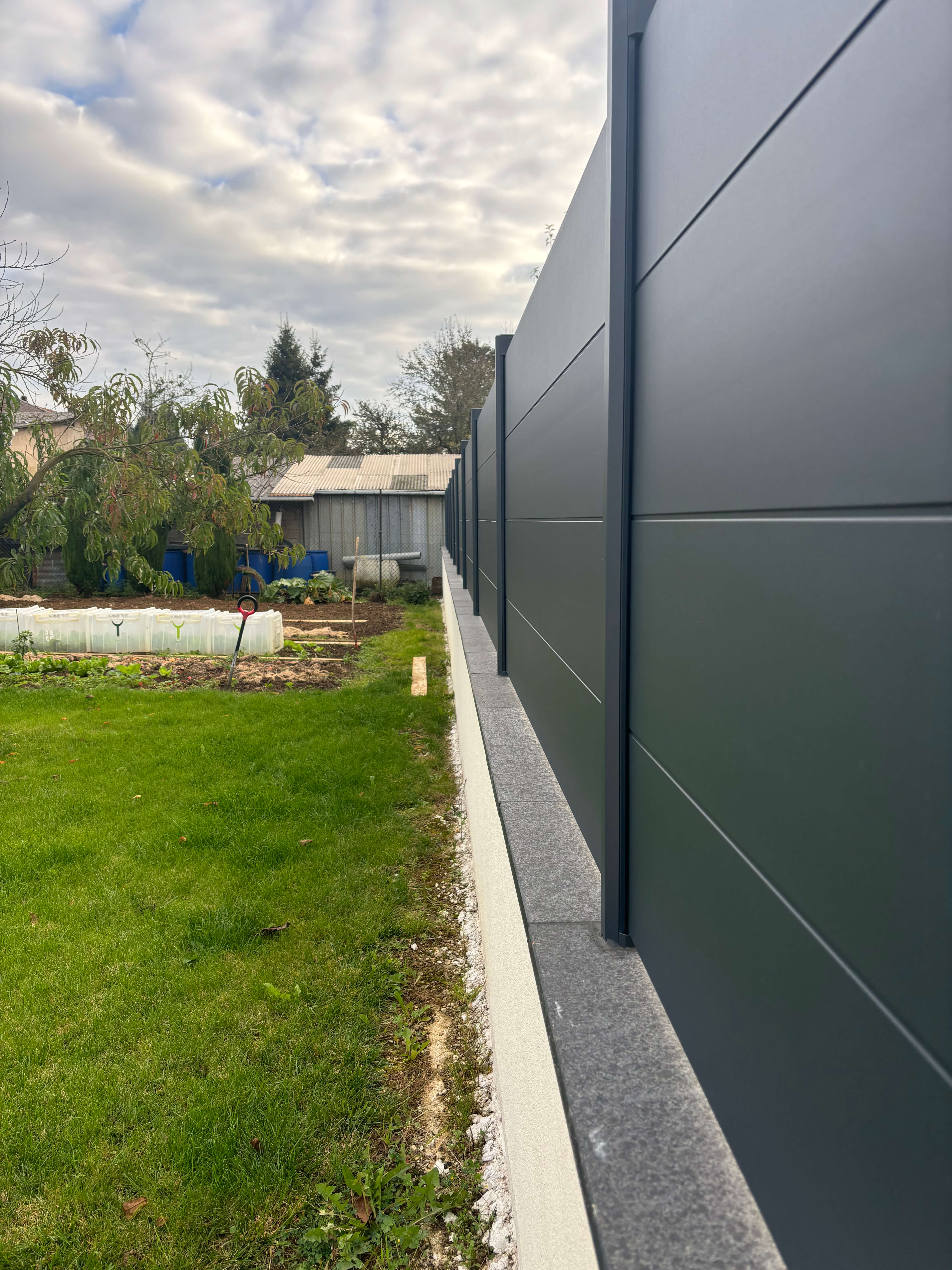 Mur coffrant avec cloture en aluminium et couvertine granit