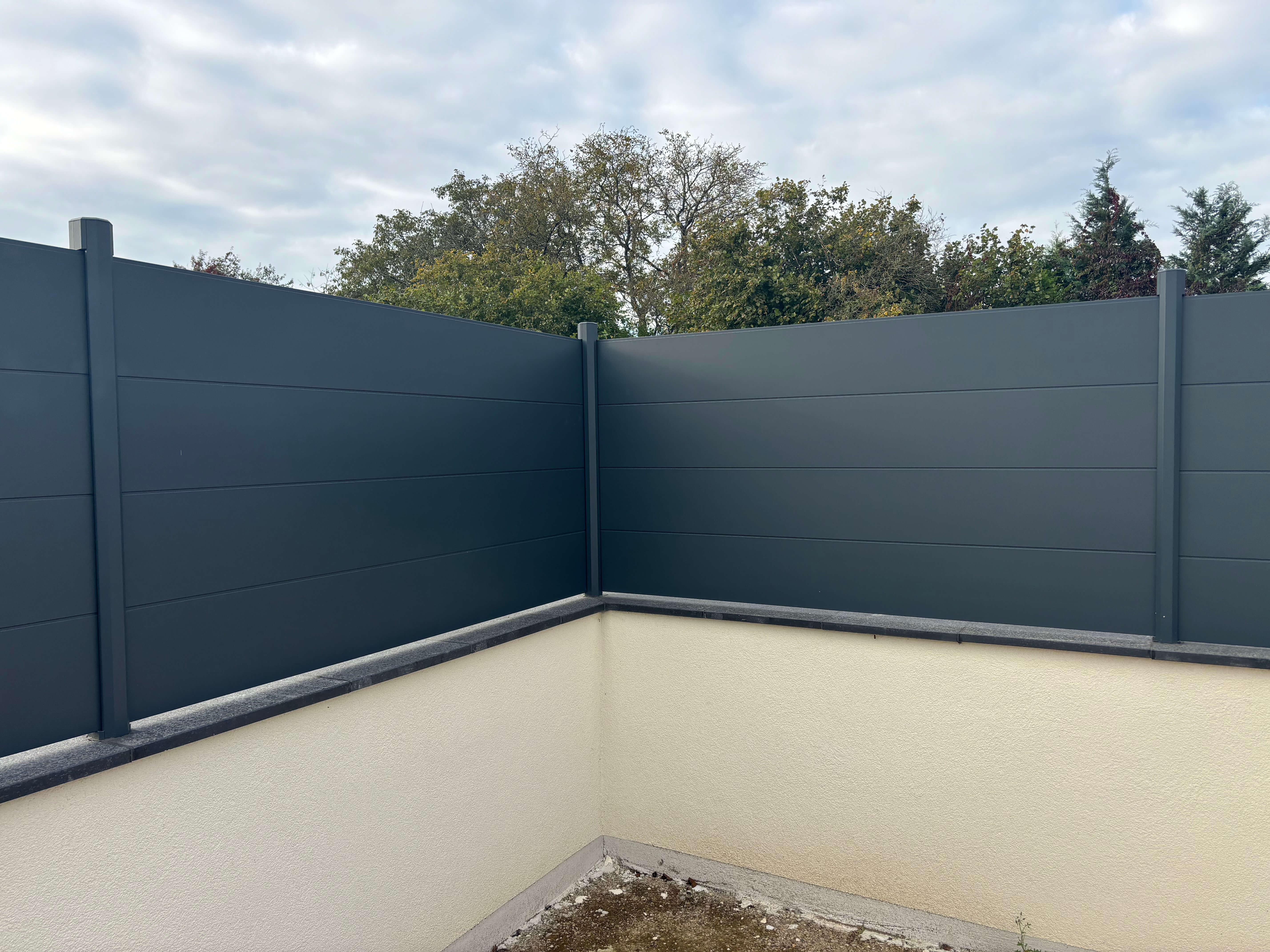 Mur coffrant avec cloture en aluminium et couvertine granit