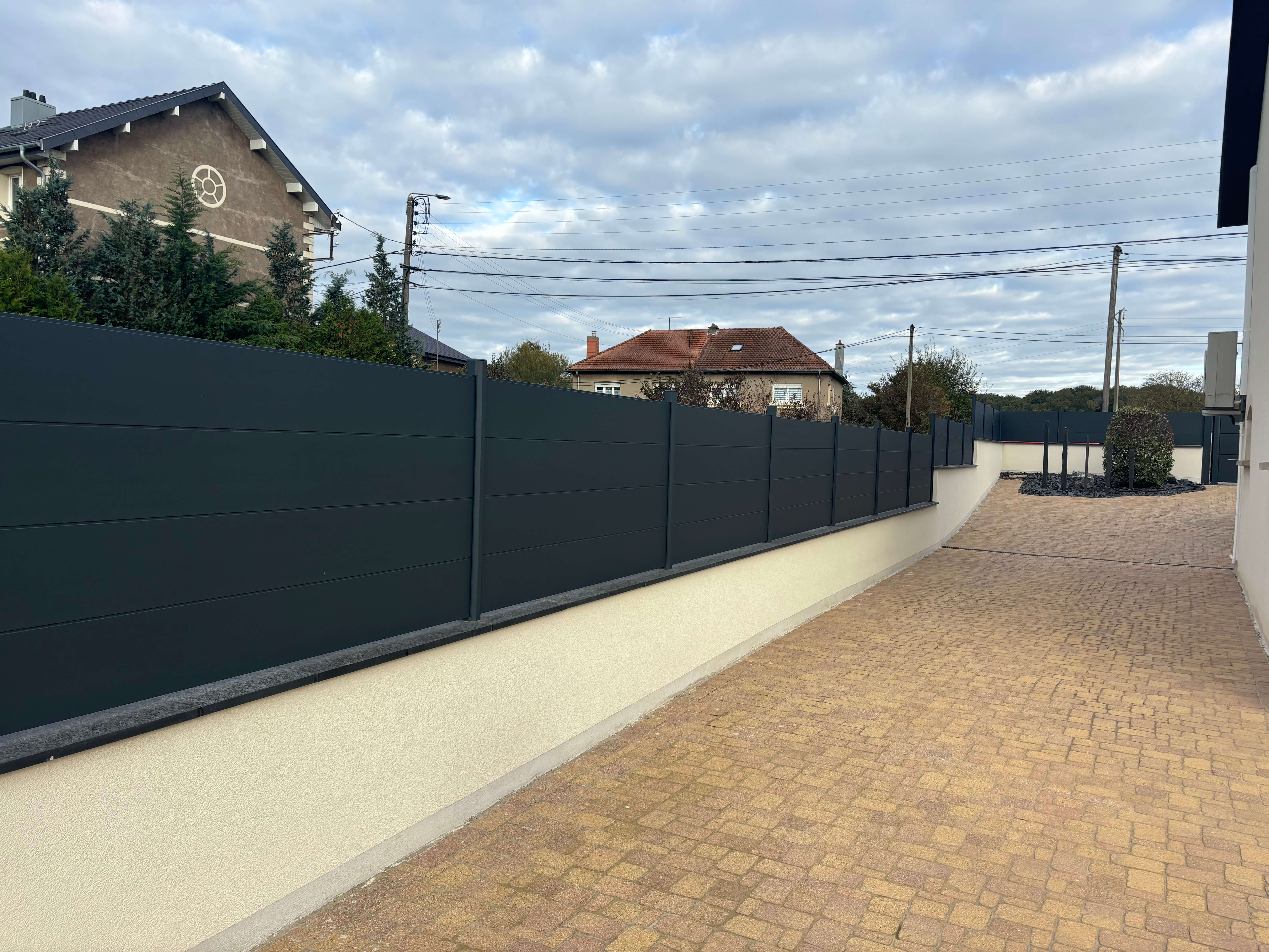 Mur coffrant avec cloture en aluminium et couvertine granit