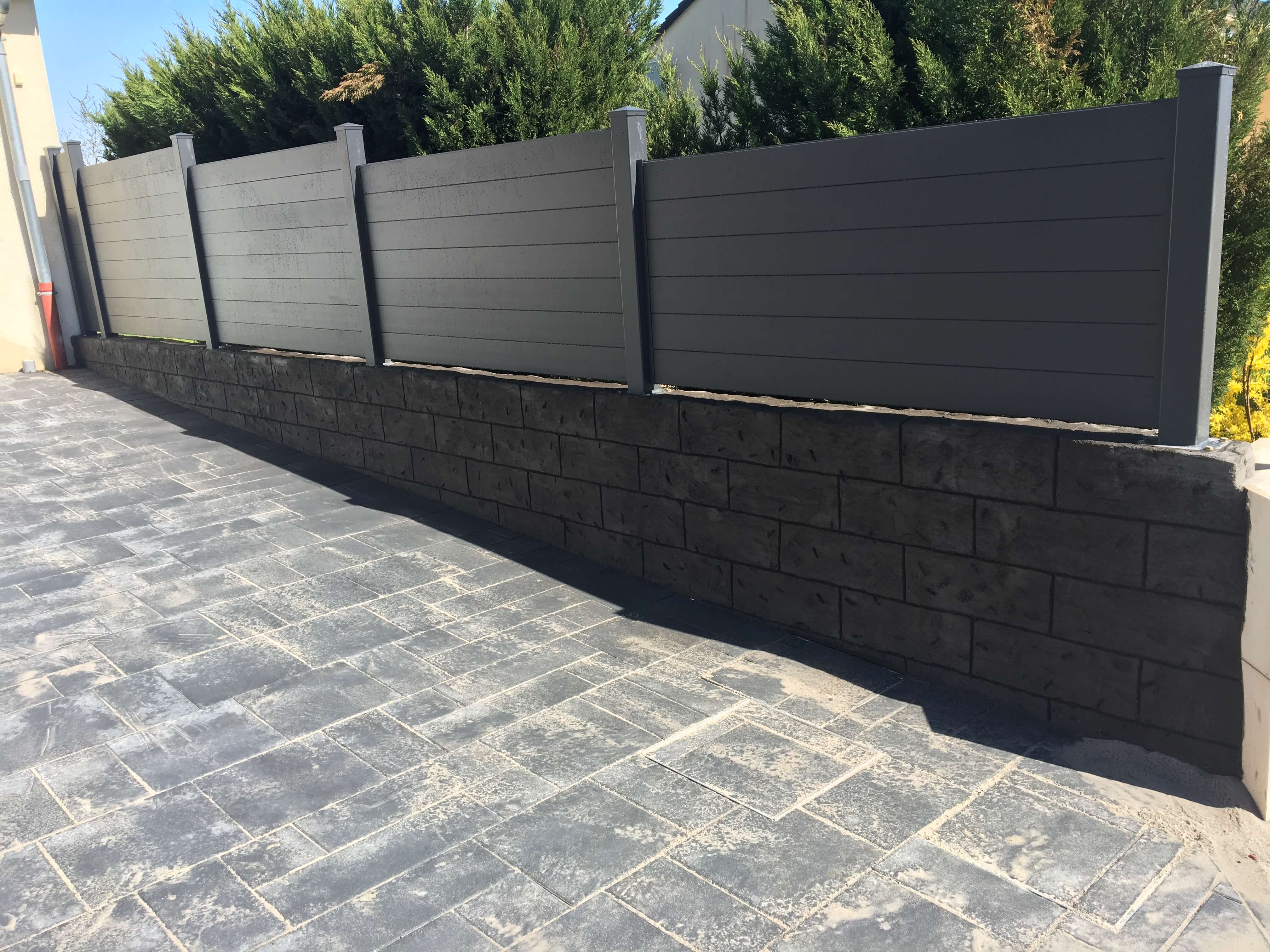 Mur rénové en enduit ciment Anthracite imitation agglo fini avec claustra en aluminium.